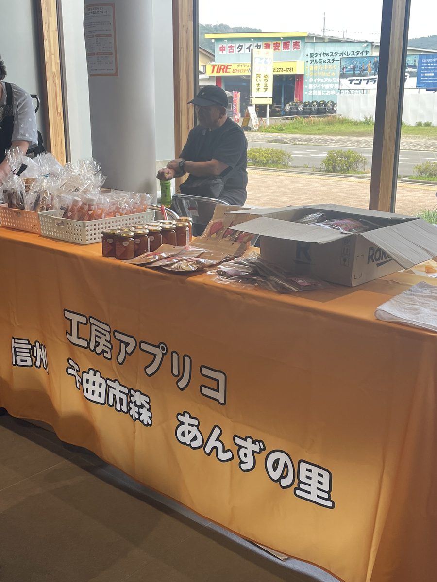 工房アプリコの横断幕とあんず加工品が並ぶ出店ブース
